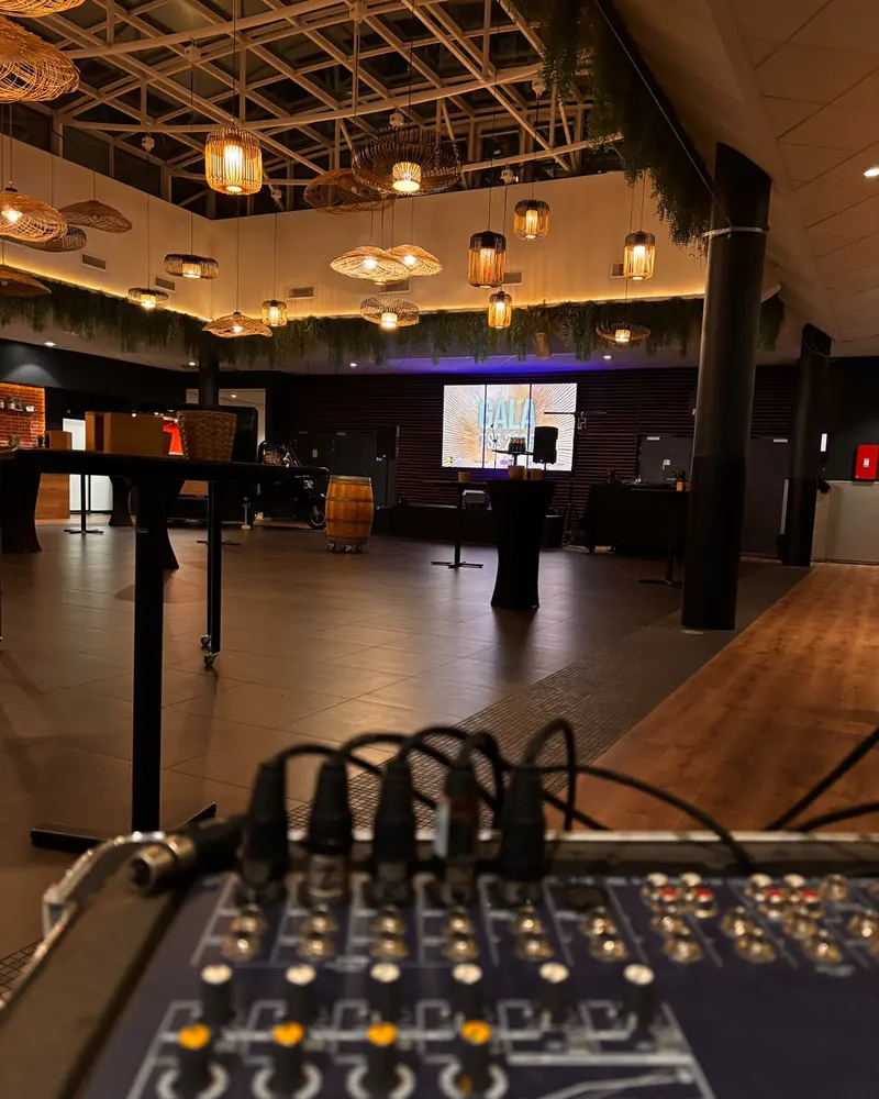 Salle de gala aux suspensions en osier, écran de projection allumé au fond, régie son au premier plan.